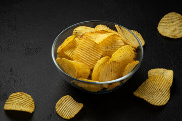 Ridged potato chips on black background 