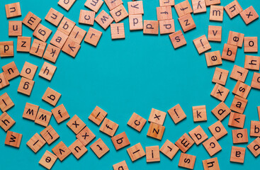 English alphabet made of square wooden tiles with the English alphabet scattered on blue background. The concept of thinking development,grammar.