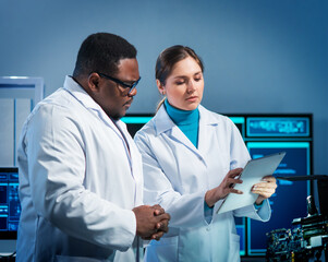 Group of microelectronic engineers discussing in a modern microprocessor manufacture lab. Workplace...