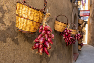 ozdobne kosze wiklinowe i warkocze czerwonej cebuli na lewacji kamienicy we Włoszech
