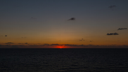 zachód słońca przy wulkanie Stromboli widocznym na horyzoncie - obrazy, fototapety, plakaty