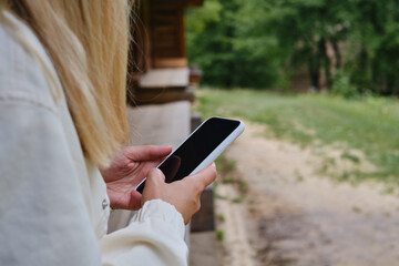 A girl on the street is holding a modern smartphone, sending a text message or using an application on her mobile phone. View city map using smartphone. Smartphone close-up