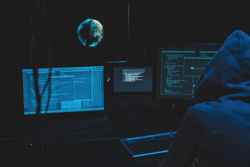 Cyber criminal hacking system at monitors, hacker attack web servers in dark room at computer with monitors sending virus using email vulneraility. Internet crime, hacking and malware concept.