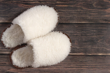 white fluffy wool slippers made of sheep's wool on a wooden background 