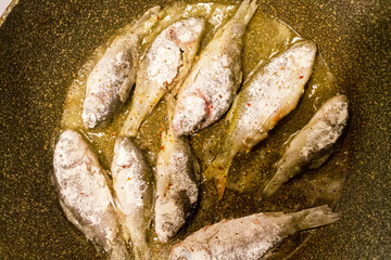 River fish is fried in a frying pan close-up.