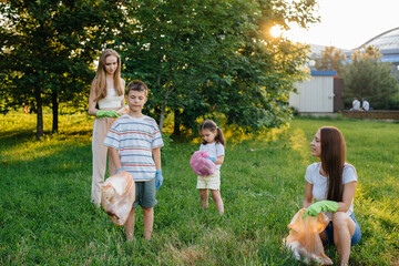 A group of girls with children at sunset are engaged in garbage collection in the park....