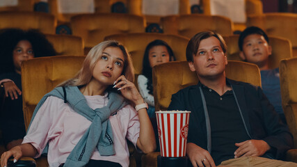 Attractive cheerful young caucasian couple laughing while watching film in movie theater. Lifestyle entertainment concept.