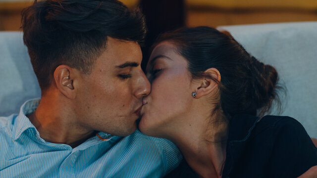 Attractive cheerful young caucasian couple kissing romantic moment while watching film in movie theater. Lifestyle entertainment concept.