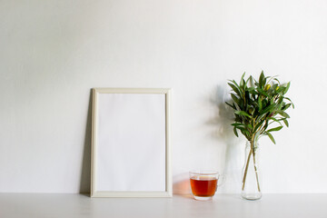 A frame with coffee and leaves on a white wall with nature light. 
