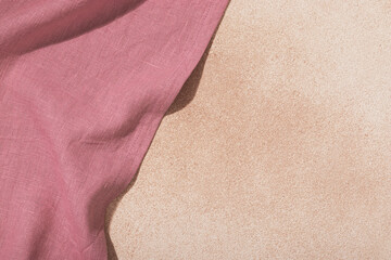 Textile pink serving napkin on beige plastered background