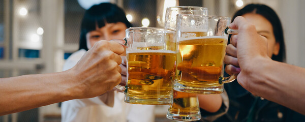 Group of happy tourist young Asia friends drinking alcohol or craft beer and having hangout party in night club. Traveler backpacker Asia people travel. Panoramic banner background with copy space.