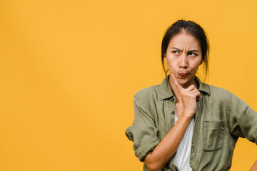 Portrait of young Asia lady with positive expression, thinks about coming holidays, dressed in casual clothing over yellow background with blank copy space. Happy adorable glad woman rejoices success.