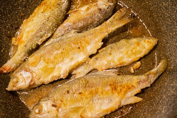 River fish is fried in a frying pan close-up.