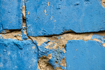 Rough cracked concrete wall painted blue. Close-up. Copy space
