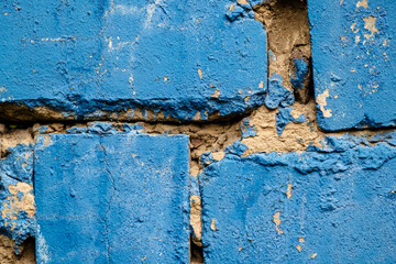 Old brick wall with uneven cement layer painted blue. Close-up. Copy space