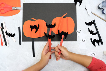 Child making pumpkins for the holiday of halloween. Funny crafts from paper. Halloween decor. Handicraft. The concept for Halloween. DIY. Children's art project, a craft for children.