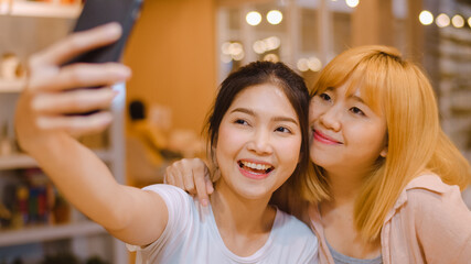 Cheerful young Asia friend clicking selfie using mobile phone at a coffee shop. Two joyful attractive Asian girls together at restaurant or cafe. Holiday activity, or modern lifestyle concept. - Powered by Adobe