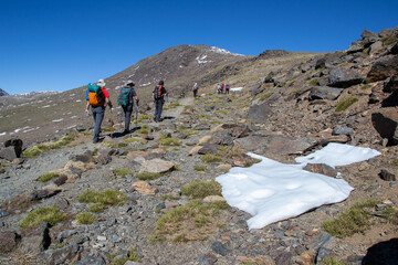hikers going up to Mulhacen through a mountainous area with a bit of snow
