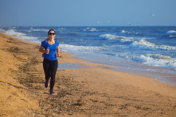 Fototapeta na wymiar woman running by the sea beach and listening music