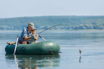 grandfather with grandson together fishing from inflatable boat