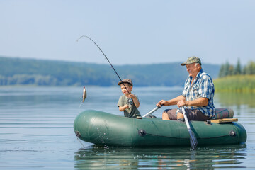 grandfather with grandson together fishing from inflatable boat