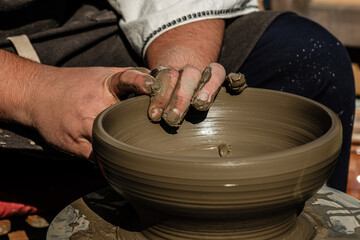 Hands of a potter shaping a clay pot on a potter wheel