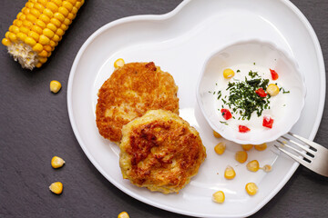 Delicious catlets on a plate with sauce of sour cream and greens close-up.