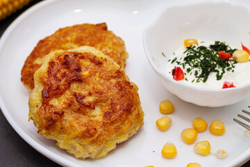 Delicious catlets on a plate with sauce of sour cream and greens close-up.