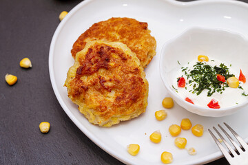 Delicious catlets on a plate with sauce of sour cream and greens close-up.