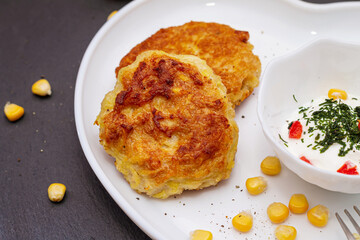 Delicious catlets on a plate with sauce of sour cream and greens close-up.