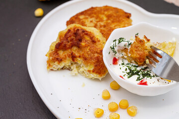 Delicious catlets on a plate with sauce of sour cream and greens close-up.