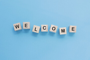 Obraz premium Word welcome on wooden cubes on blue background