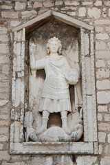 Stone sculpture of Saint Michael the Archangel killing a dragon, detail on public library building in Sibenik, Croatia