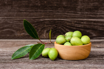 Olives fruit with green leaf in wooden bowl on wood table.