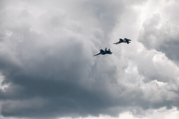 Naklejka na ściany i meble Combat aircraft are flying against the background of the sky. Cloudy sky. Beautiful fighters.