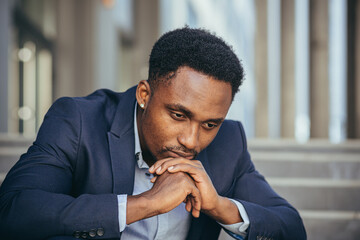 African american businessman in business suit frustrated got bad news from work, fired depressed sitting on stairs, close-up portrait photo