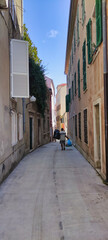 A man with garbage bags walks along a narrow street in the historical part of the city of Zadar. Croatia. Europe