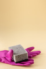 Gray dishwashing sponge and pink rubber gloves on neutral beige background, cleaning concept