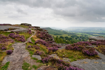 Narrow footpath runs precariously close to the edge of Curbar Edge on a damp grey summer morning.