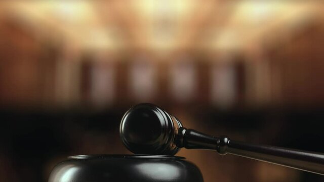 Judge is hitting gavel off a block in courtroom. Gavel is being struck to decide an auction or guilty verdict in court