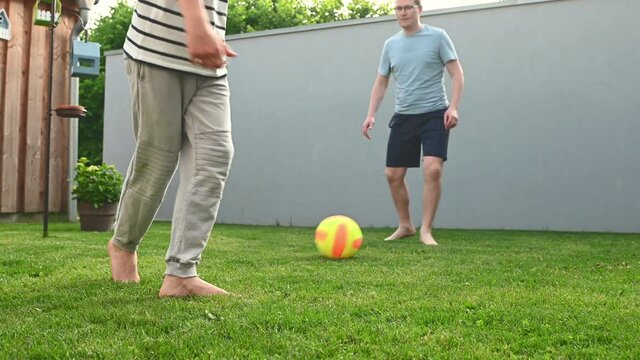 4K 60fps video of happy young father playing football and having fun with his son in backyard at sunny summer day