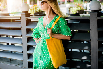 Young beautyful woman with yellow linen eco bag on city background.