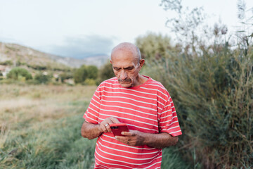 Middle-aged man using a mobile phone while enjoying a day outdoors in the nature. Technology concept.