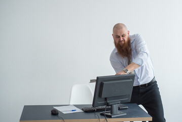 Stressed crazy businessman smashing his computer in office using ax problem concept. The man has...