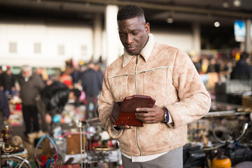African American man chooses antiques on the flea market