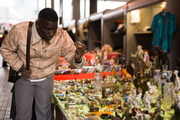 African American man chooses antiques on the flea market