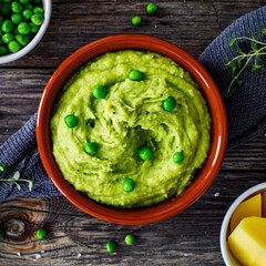 Puree - mashed potatoes with green pea in bowl on wooden table
