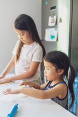 Fototapeta premium Asian girl in casual dress having fun while make pizza with prosciutto, tomato, cheese, vegetables in home kitchen. family and relationship concept