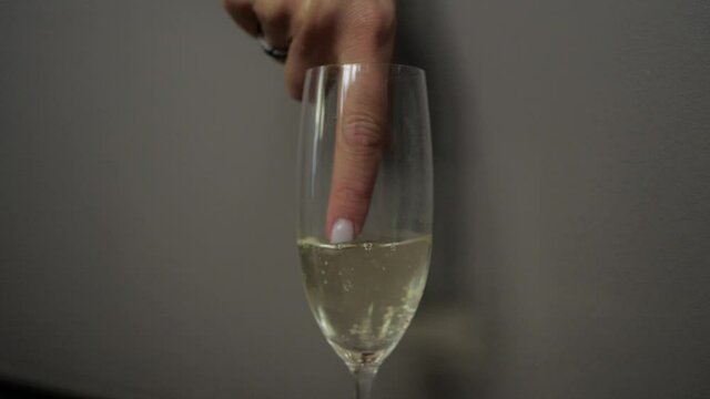 a woman's finger with a beautiful manicure slowly stirring champagne in a glass, forming. High quality FullHD footage