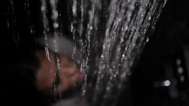 a brunette girl in a white shirt stands under the shower and strokes her hair with her hands, view from above. High quality FullHD footage